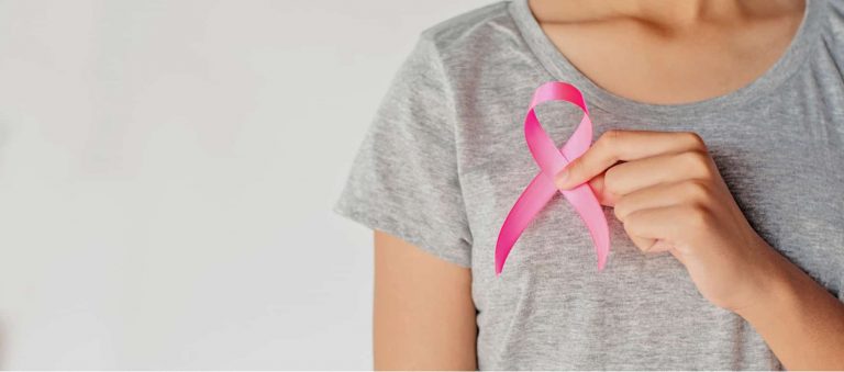 a woman holding a pink awareness ribbon to represent mastectomy, breast reconstruction, and breast cancer