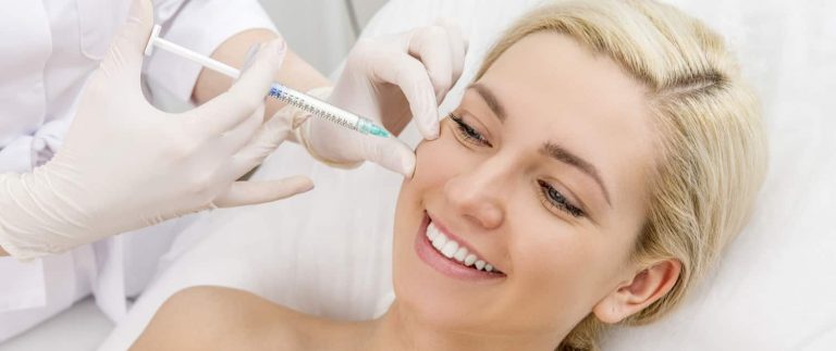 A woman smiling while having face fillers injected