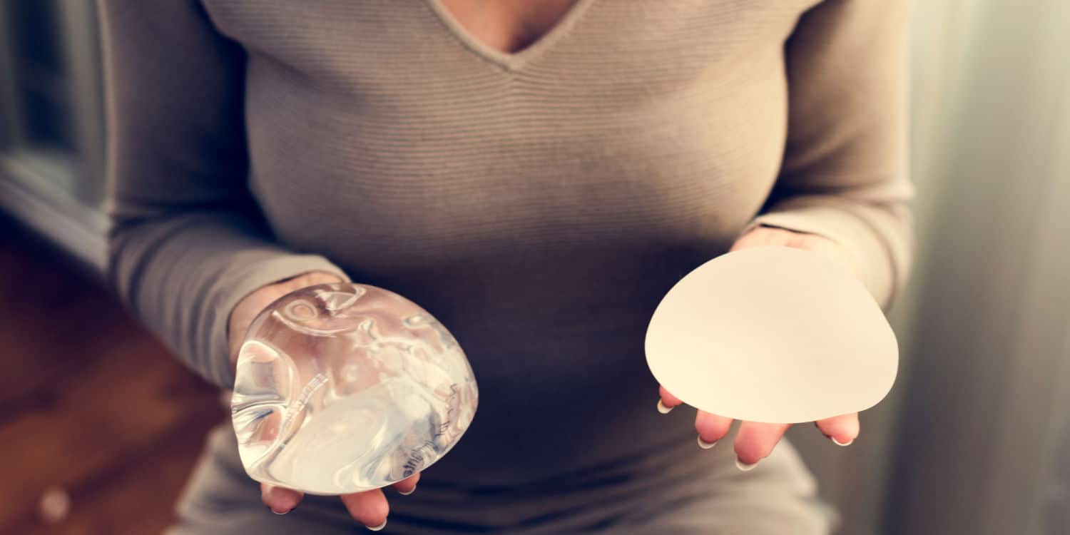A woman holding two types of implants that could be used for breast implant revision